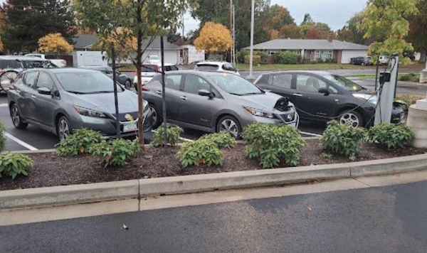 Two electric vehicles charging and one waiting to charge