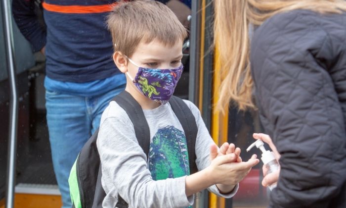 Elementary student getting off bus with mask