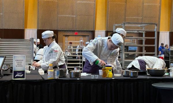 Students at a culinary competition cooking & plating food.