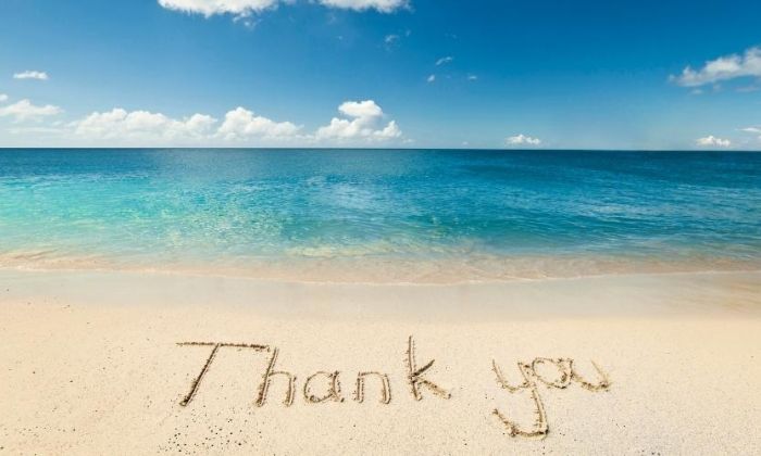 Thank you written in sand on beach in front of ocean