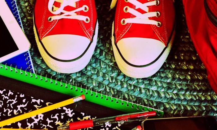 Top down view of an assortment of school supplies and red Converse