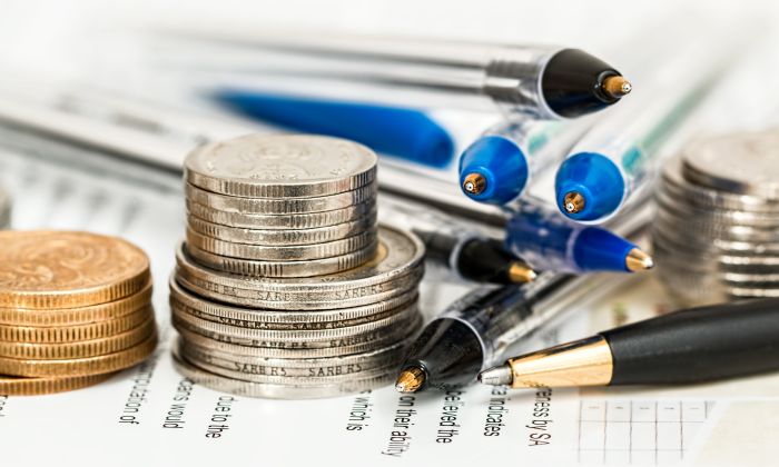 Stacked coins next to pens