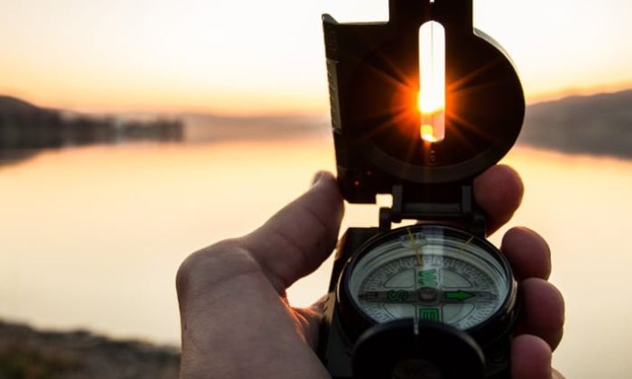 Compass in someone's hand at sunrise/sunset