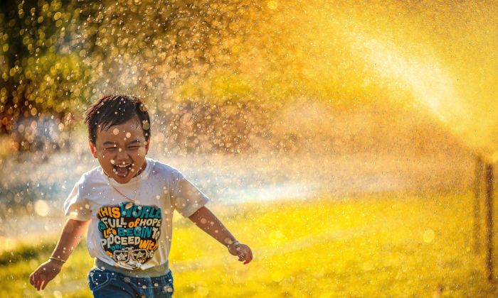 little boy running through sprinkler